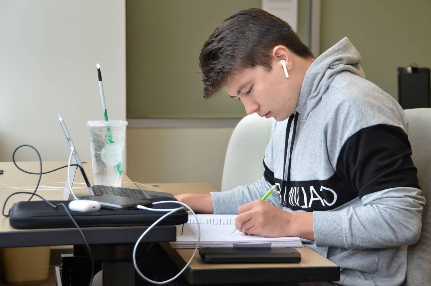 在书桌前学习的学生，有铅笔、笔记本和电脑